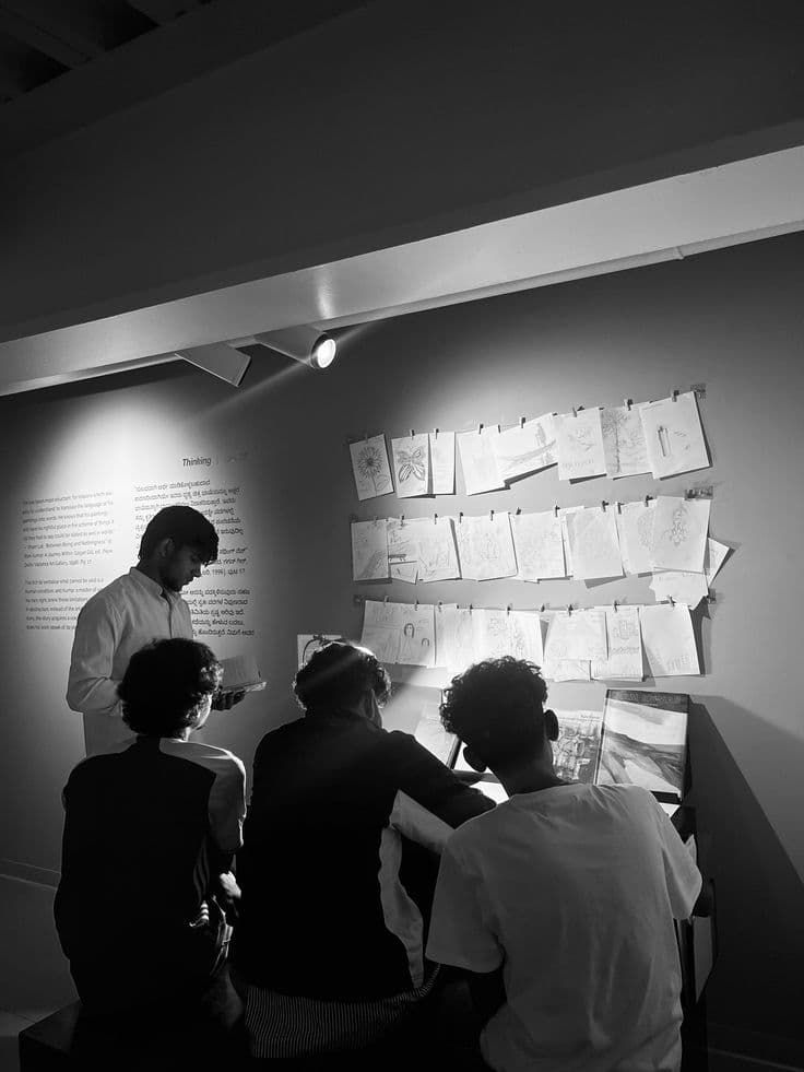 Varias personas observan una pared con bocetos y notas colgadas